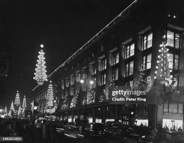 Illuminated Christmas tree and Christmas lights along the facade of Selfridges department store on Oxford Street, in the West End of London, England,...