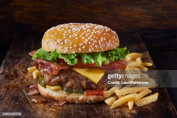 juicy ground pork and bacon cheeseburger with fries - hamburger stockfoto's en -beelden