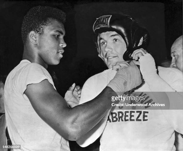 Light heavtweight Cassius Clay gives an assist to heavyweight challenger Ingemar Johansson before going a couple of rounds as his sparring partner...
