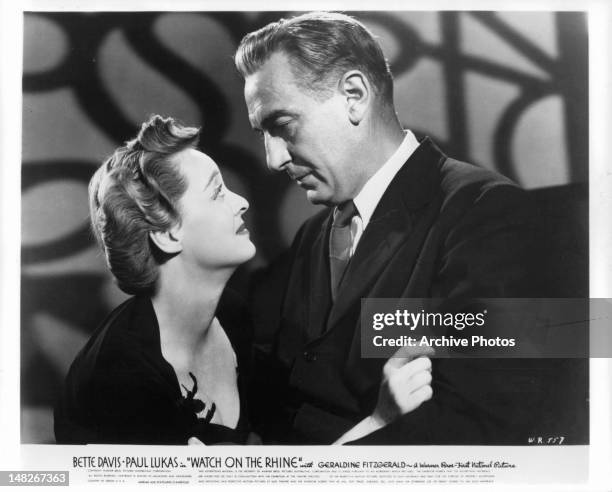 Bette Davis looking up at Paul Lukas in a scene from the film 'Watch On The Rhine', 1943.