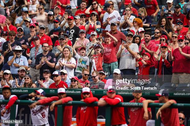 Washington Nationals fans cheer behind the dugout during the ninth inning of the game between the Washington Nationals and the Cleveland Guardians at...