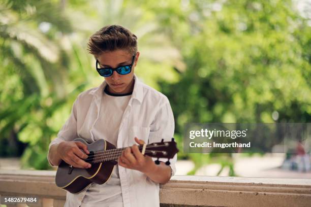 teenager spielt ukulele im öffentlichen park - ukulele stock-fotos und bilder