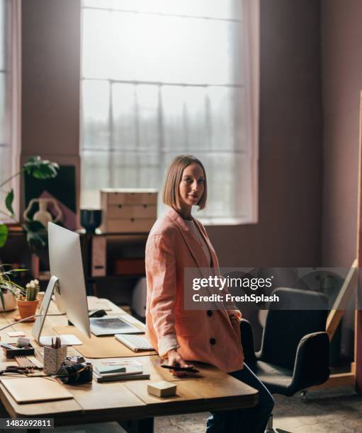 a happy beautiful blonde businesswoman looking at camera while working in her office - red pen single object stock pictures, royalty-free photos & images