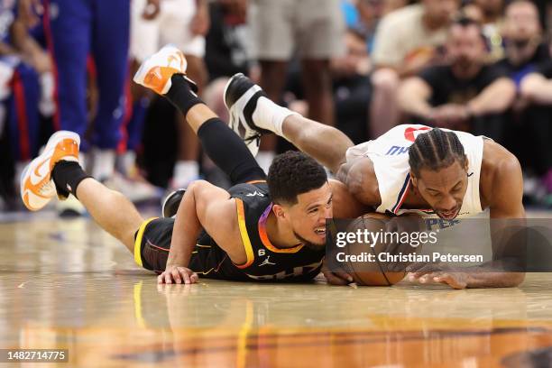 Devin Booker of the Phoenix Suns and Kawhi Leonard of the LA Clippers dive for a loose ball during the first half Game One of the Western Conference...