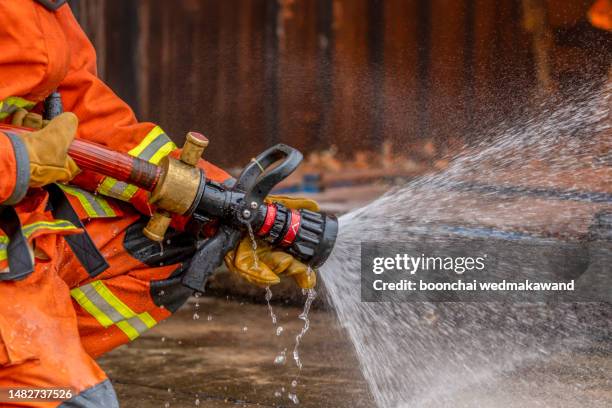 firefighter holding fire hose outdoors. - extinguishing stock pictures, royalty-free photos & images