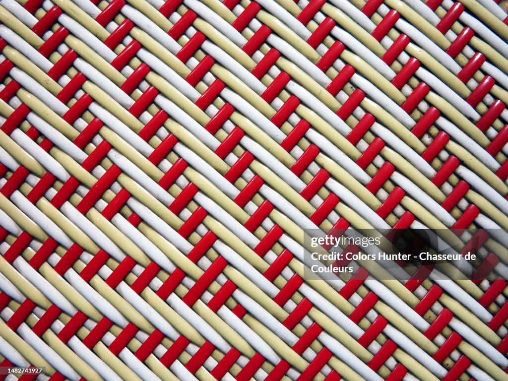 Close-up of the red and white plastic braiding of the seat of a Parisian bistro chair
