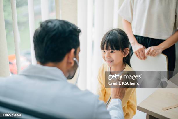 photo of a doctor examining a little girl with a stethoscope in a clinic. - kinderarts stockfoto's en -beelden