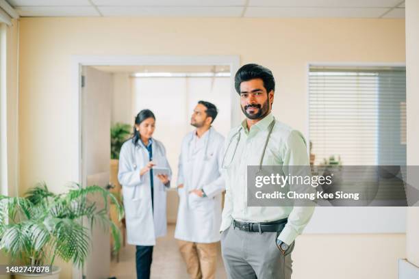 confident male doctor with medical team in background - succession planning stock pictures, royalty-free photos & images