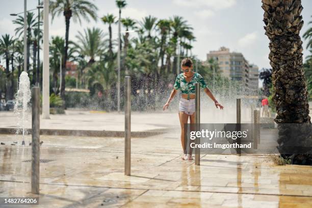 adolescente caminando por la fuente de los rociadores de la ciudad en la calle de la ciudad. - fuente estructura creada por el hombre fotografías e imágenes de stock