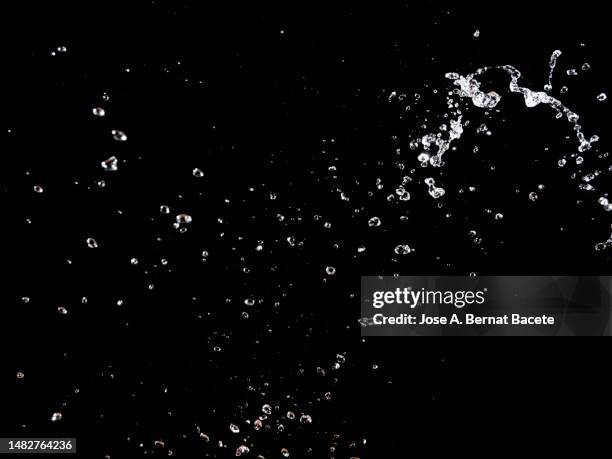 drops and splashes of water in motion on a black background. - gota de agua salpicando fotografías e imágenes de stock
