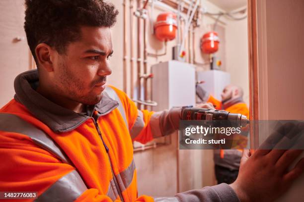 heating engineers installing system - hot works stock pictures, royalty-free photos & images