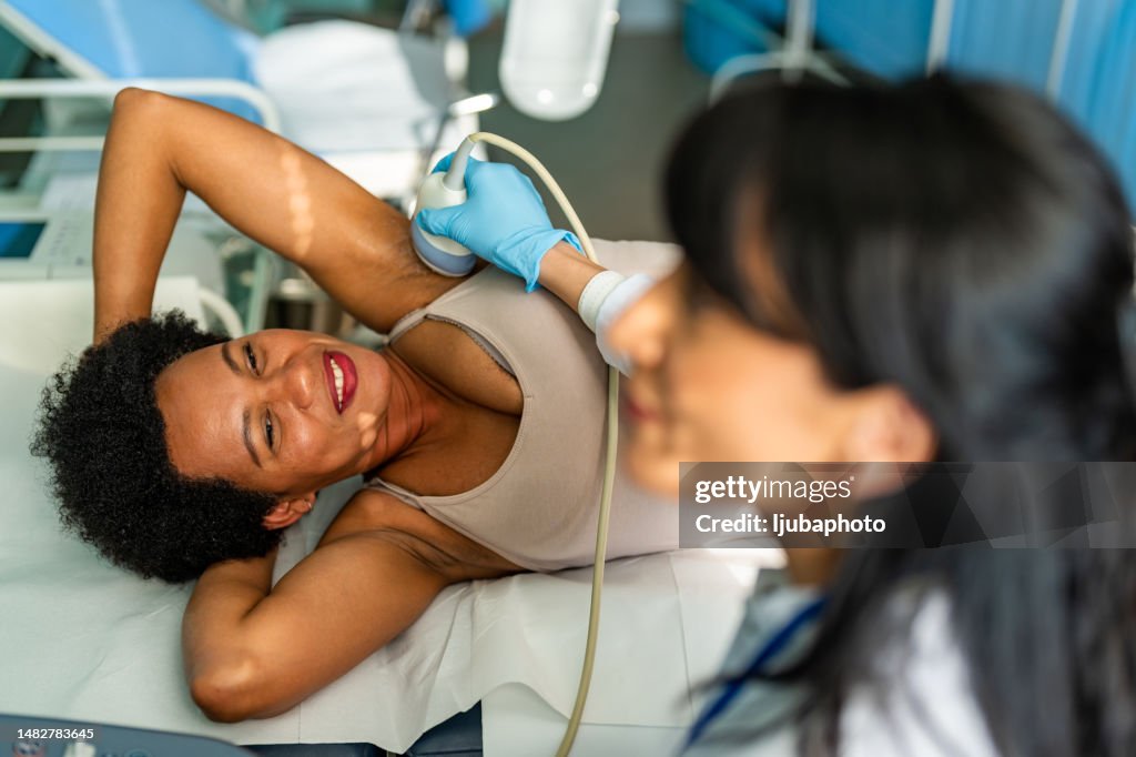 Médico que realiza un examen de ultrasonido de la mama de la paciente en la clínica