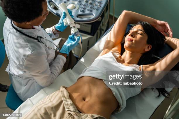 mid adult female doctor using ultrasound scanner - gynaecoloog stockfoto's en -beelden