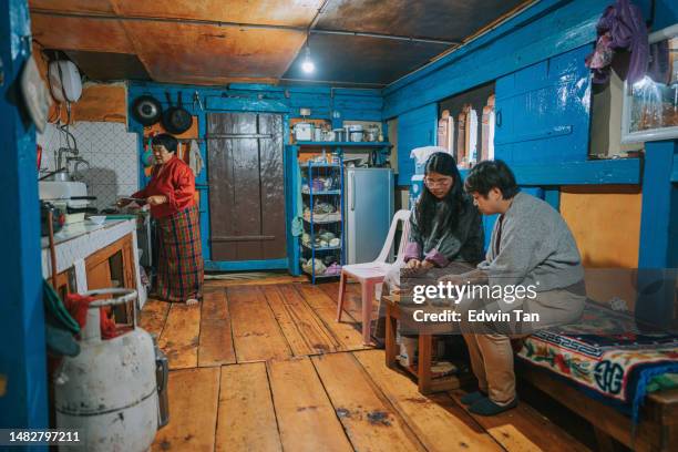 asian chinese female tourist experiential travel learning cooking traditional bhutanese food in farmhouse preparing dinner with bhutanese women - experiential vacations stock pictures, royalty-free photos & images