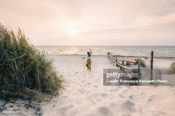 woman running on the beach at sunset, baltic sea, germany. - beach dunes foto e immagini stock