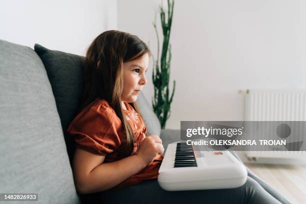 preschool age girl playing piano at home. learning musical hobby - keyboard musical instrument child stock-fotos und bilder