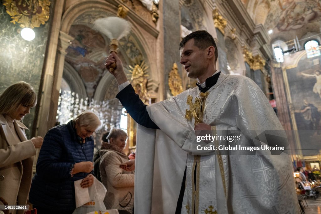 A priest sprinkles holy water during the Easter baskets’ consecration ...