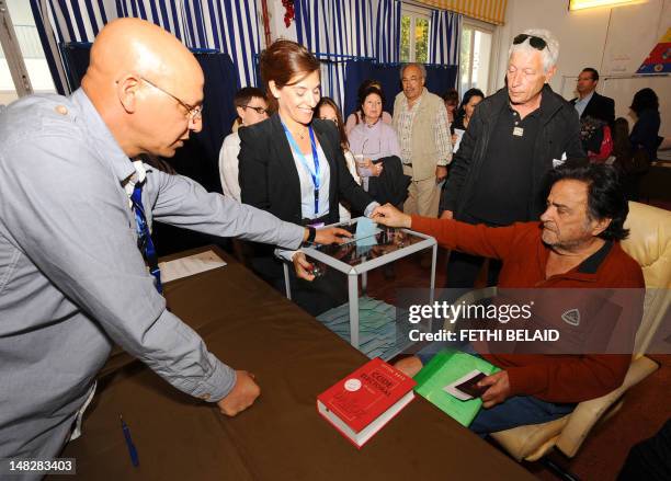 French citizens living in Tunisia come out of a voting booth as they prepare to cast their ballot at a polling station, on April 22 in La Marsa near...