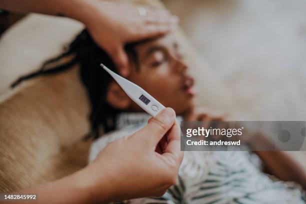 mother taking care of her son lying down with a fever - heat illness stock pictures, royalty-free photos & images