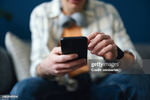 hombre anónimo sentado y usando su teléfono móvil - zoom hacia dentro fotografías e imágenes de stock