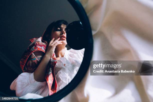 young woman looking in the mirror and taking picture of herself - oberteil stock-fotos und bilder