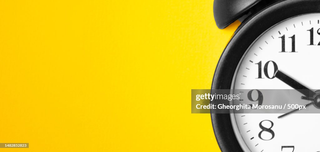 Ringing twin bell vintage classic alarm clock on yellow pastel paper,Romania