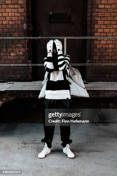 desperate young man hiding his face modern fashion outfit portrait - schöne menschen stock pictures, royalty-free photos & images