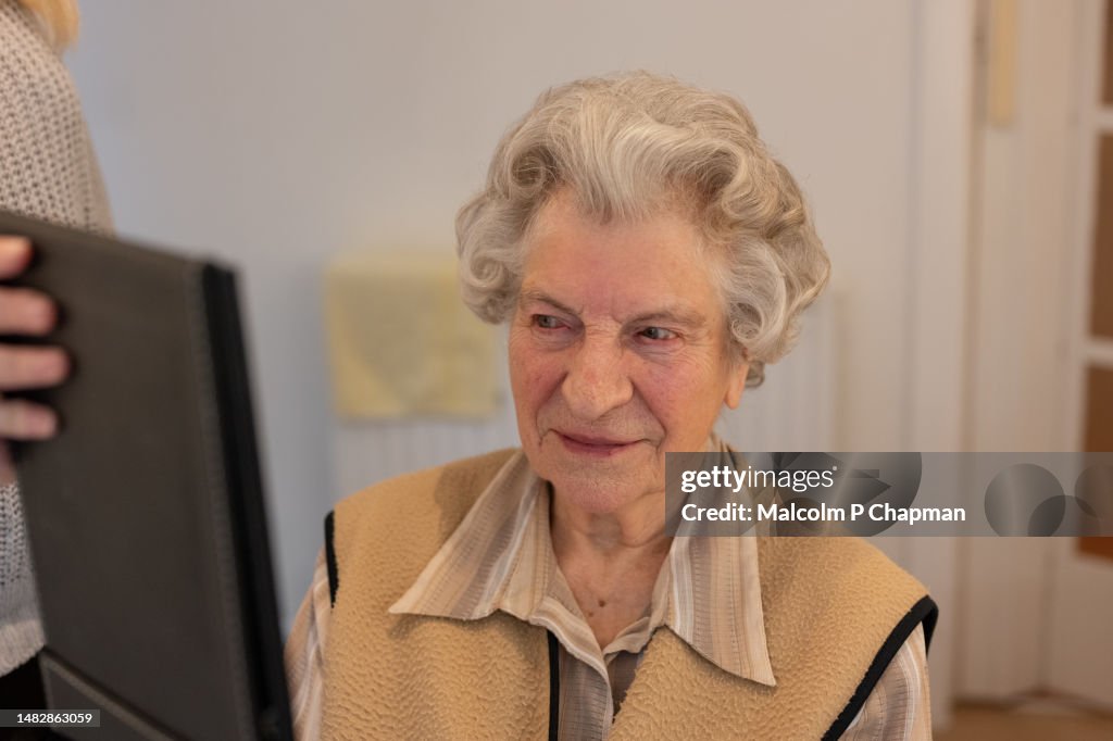 Senior woman shown new hair style by hairdresser during home salon visit