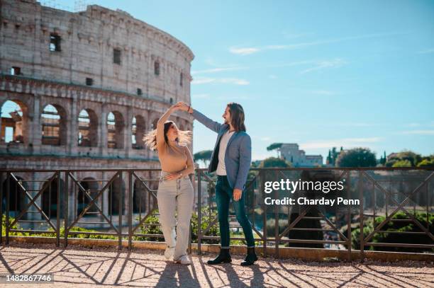 portrait of couple holding hands and dancing in front of colosseum - rome colosseum stock pictures, royalty-free photos & images