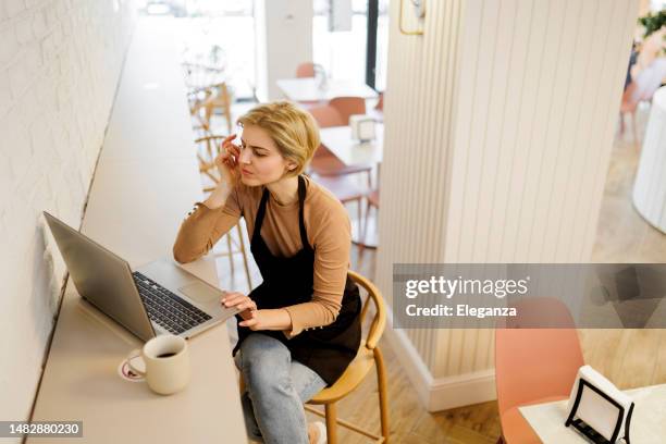 stressed female owner of cake shop working on laptop - overworked waitress stock pictures, royalty-free photos & images