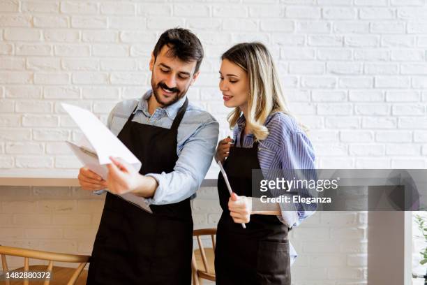 team of waiters working at a restaurant and looking at the menu- food service occupation concepts - pub reopening stock pictures, royalty-free photos & images