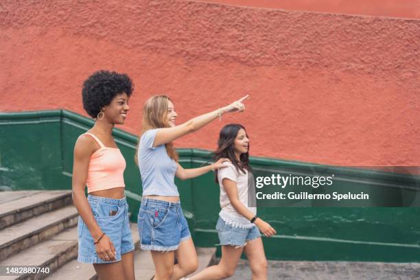 woman pointing ahead while walking with friends outdoors - weg wijzen stockfoto's en -beelden