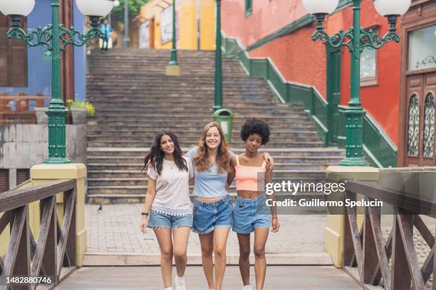 multiethnic friends walking along a bridge together - lima peru foto e immagini stock