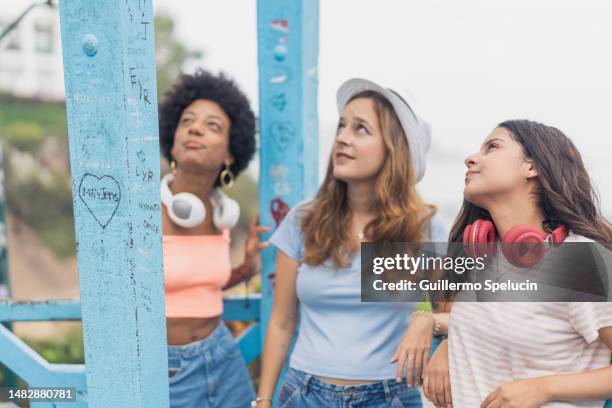 three tourist reading writing notes of love in a bridge - truehearts stock pictures, royalty-free photos & images