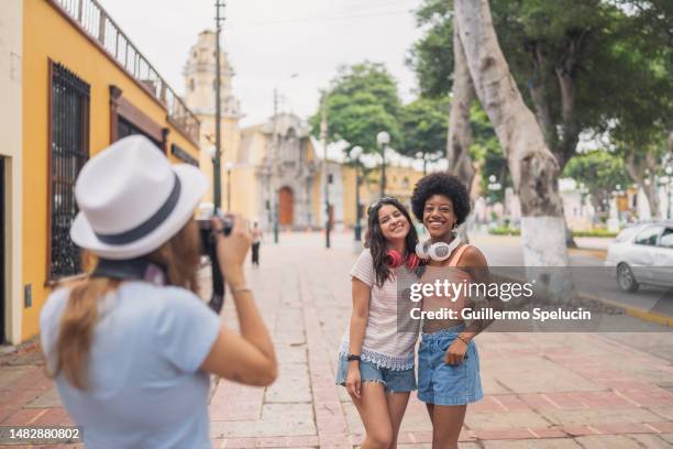 woman taking a photo of friends on the street - lima perú fotografías e imágenes de stock