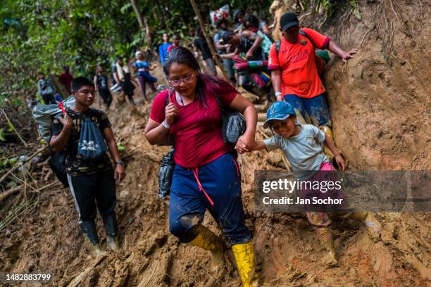 Ecuadorian migrants climb down a muddy hillside trail in the wild and dangerous jungle on November 20, 2022 in Darién Gap, Colombia. Tens of...