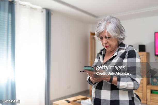 the older woman uses the trelephono in the living room of her house, looking messages - alcantara spain bildbanksfoton och bilder