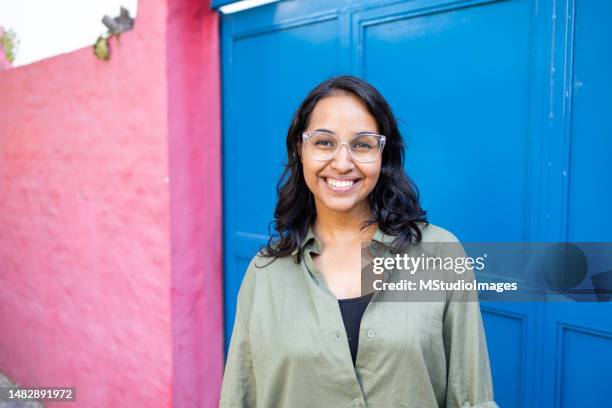 portrait of smiling woman standing on the street - mid adult stock pictures, royalty-free photos & images