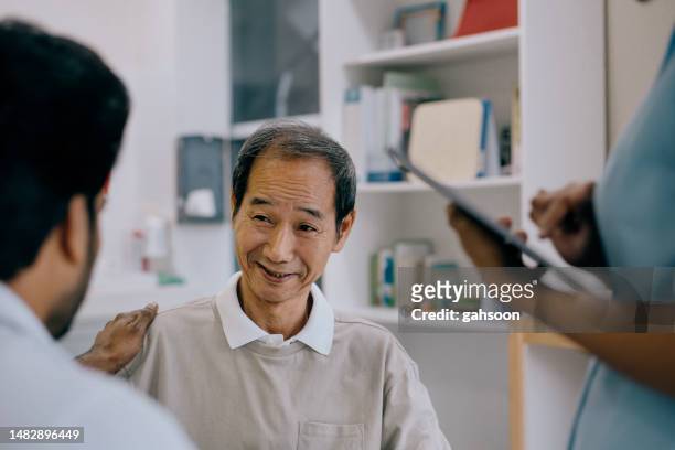doctor encouraging senior patient at clinic - elderly chinese man stock pictures, royalty-free photos & images