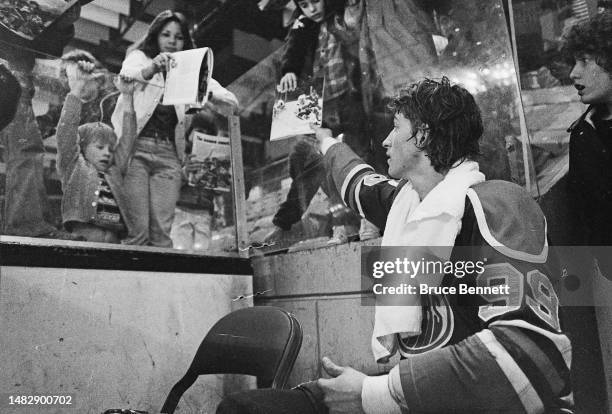 Wayne Gretzky of the Edmonton Oilers signs autographs from the penalty box during his last WHA game in April 1979.