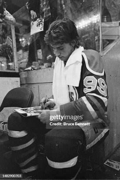 Wayne Gretzky of the Edmonton Oilers signs autographs from the penalty box during his last WHA game in April 1979.