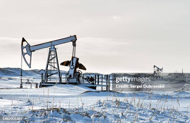 oil well with oil pump in winter snow sunny day - oil well stock pictures, royalty-free photos & images