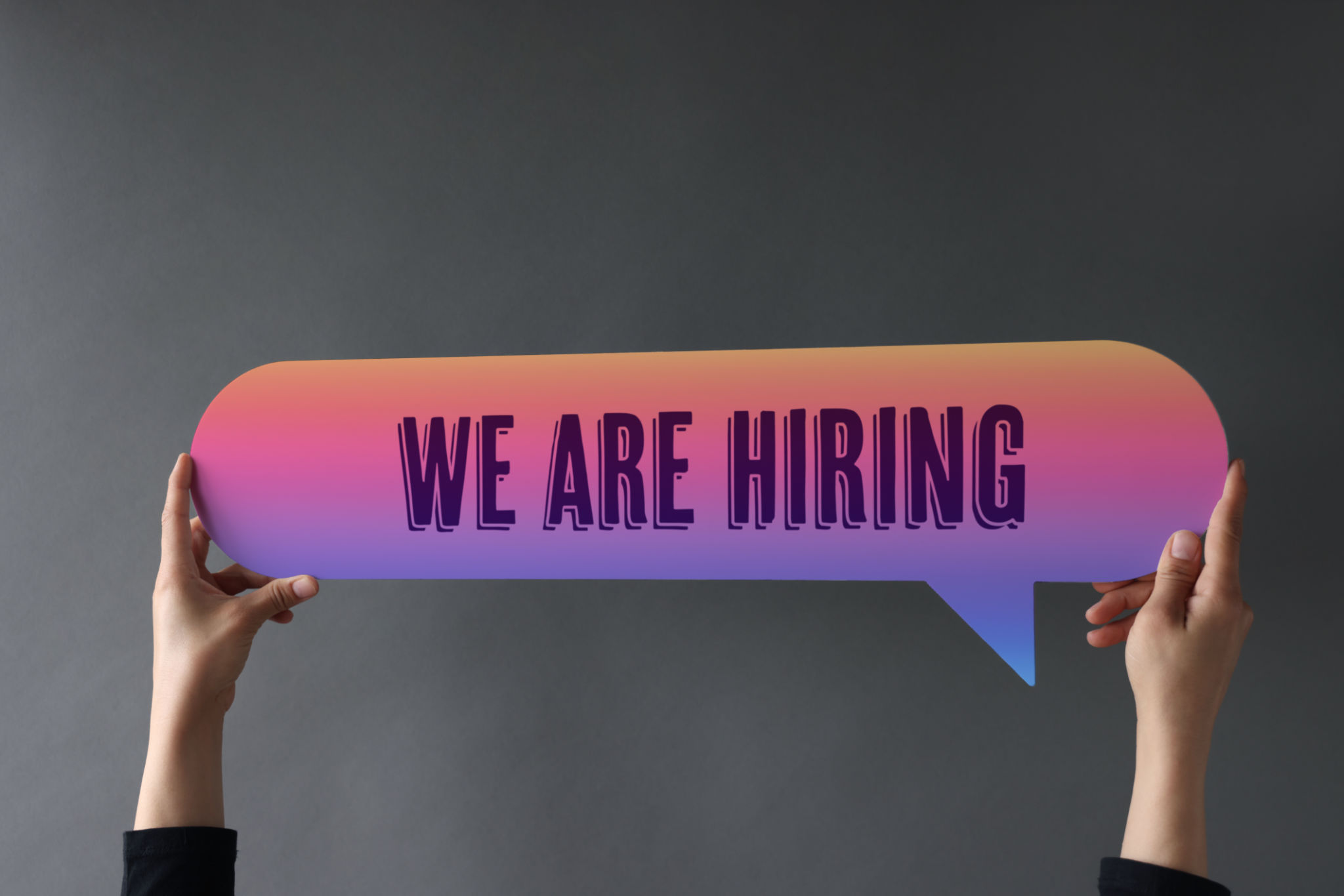 Hand holding speech bubble with we are hiring word Hand holding speech bubble with we are hiring word