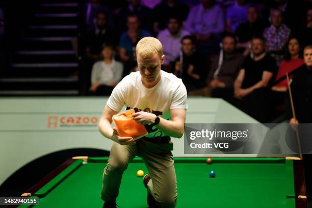 Just Stop Oil protester jumps on the table and throws orange powder during the first round match between Robert Milkins and Joe Perry on day 3 of the...