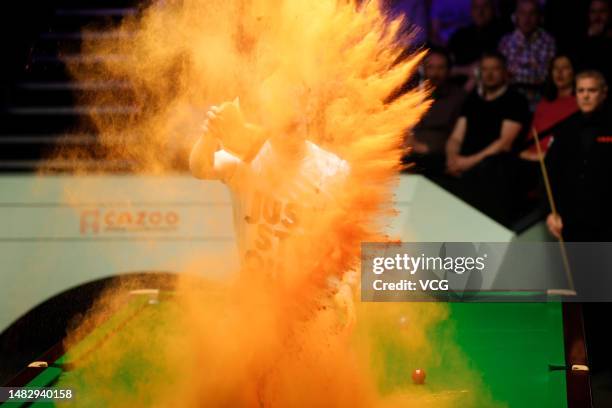 Just Stop Oil protester jumps on the table and throws orange powder during the first round match between Robert Milkins and Joe Perry on day 3 of the...