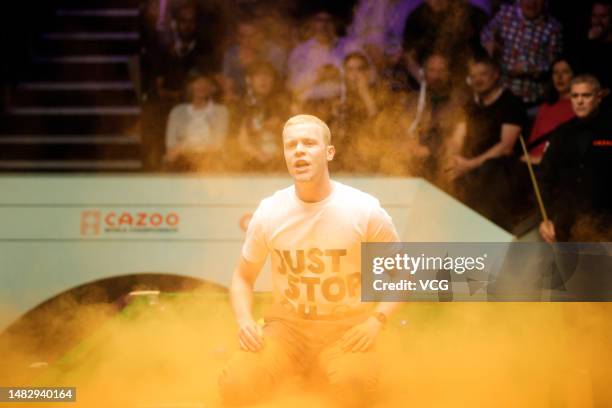 Just Stop Oil protester jumps on the table and throws orange powder during the first round match between Robert Milkins and Joe Perry on day 3 of the...