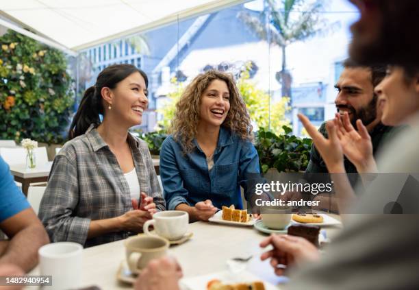 friends looking very happy talking at a cafe - coffee break party stockfoto's en -beelden