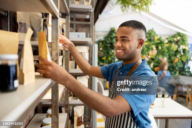 vendedor organizando productos para exhibir en una cafetería - part time worker fotografías e imágenes de stock