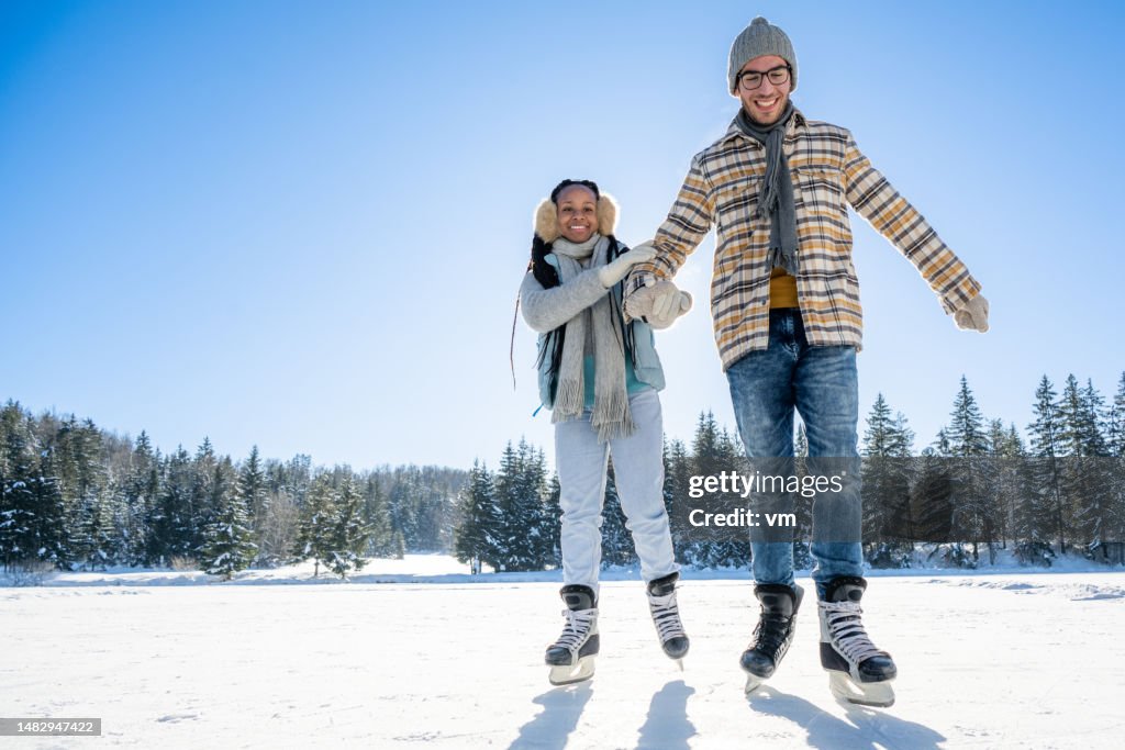 Happy father and daughter ice skating on frozen lake