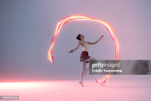 beautiful female dancer leaping in multicolor light ribbon - flowing stock pictures, royalty-free photos & images